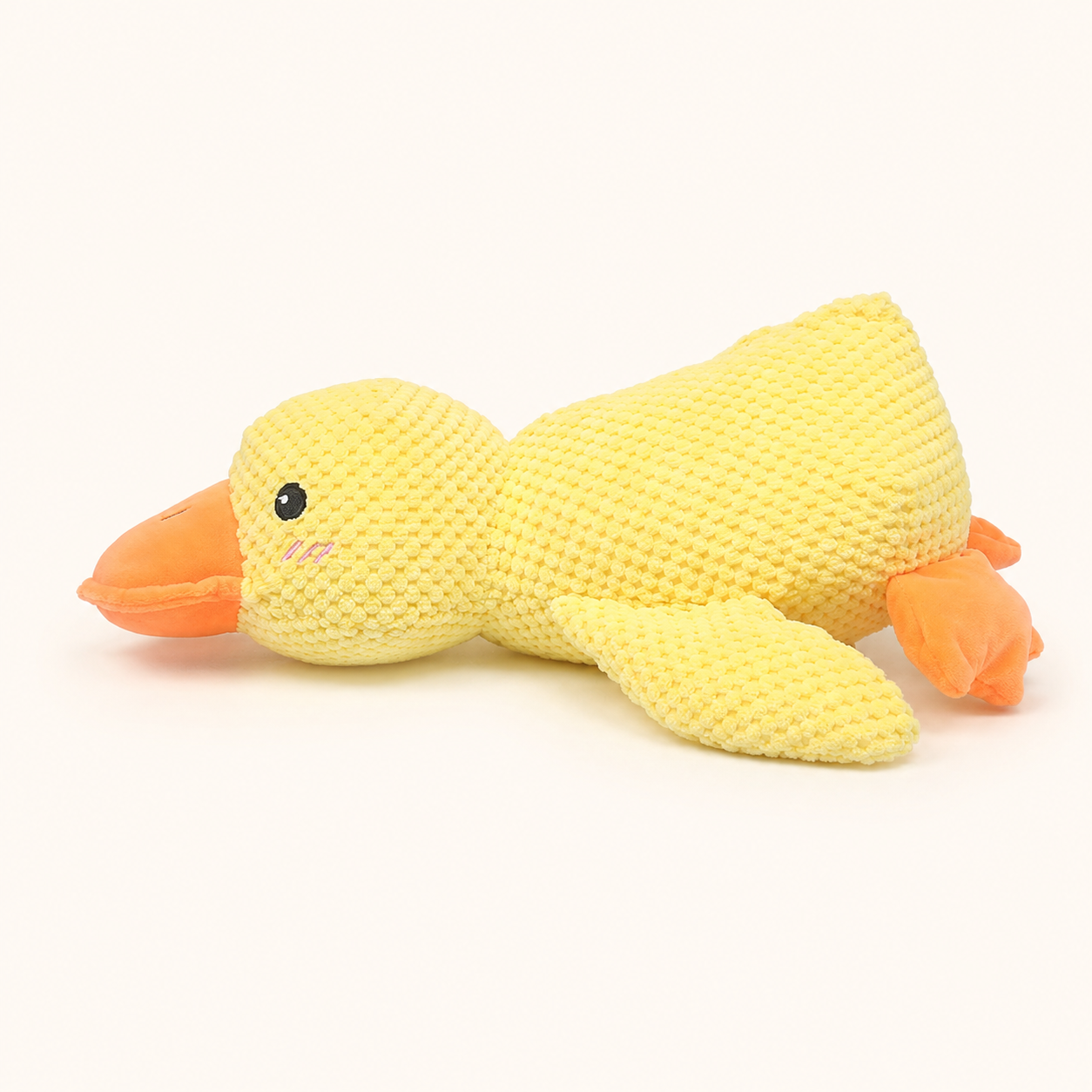 Large yellow plush squeaky duck dog toy on cream background
